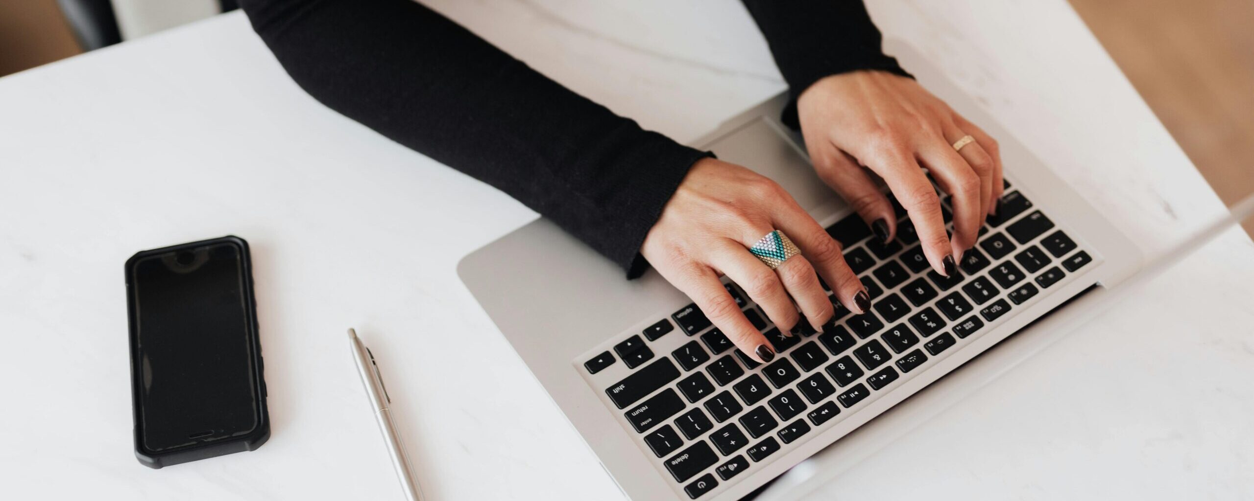 Manos de una persona en una computadora generando contenido digital.